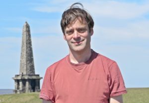 Person standing in front of monument on a green hill